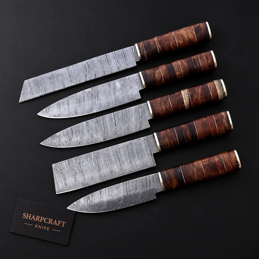 Five Damascus kitchen knives with brown stacked wood handles and brass bands on black background beside a Sharpcraft Knife card