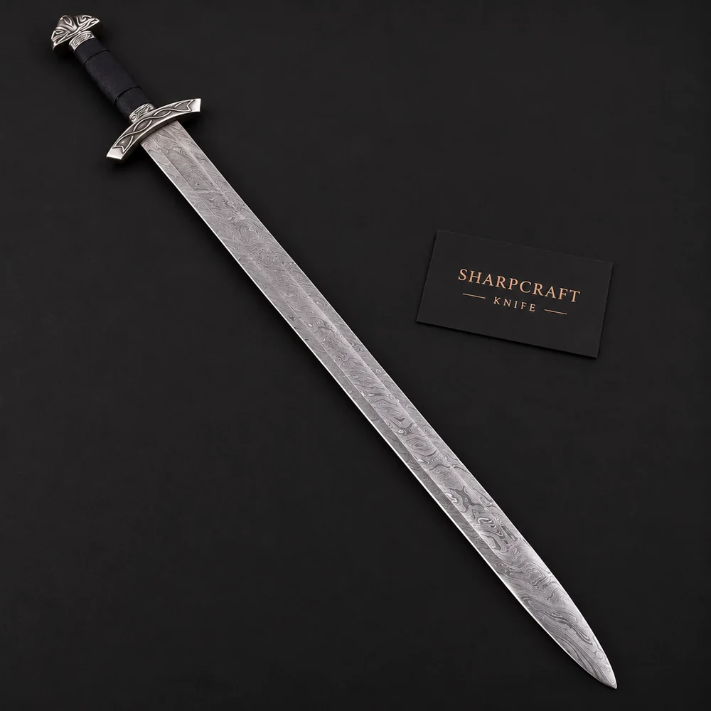 Damascus Viking sword with dark handle and silver Norse knotwork guard on black background beside a Sharpcraft Knife card