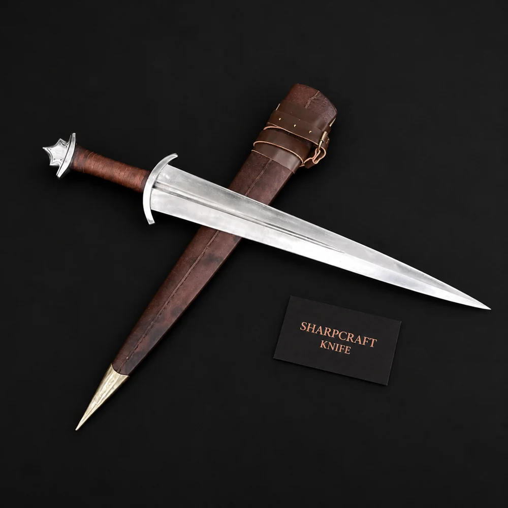 Silver medieval sword with brown leather grip and matching brown scabbard on black background beside a Sharpcraft Knife card